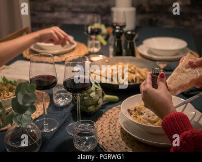 Bis spät in die Nacht Abendessen zu Hause. Freunde Pasta Essen und Getränke Wein am Tisch. Stockfoto