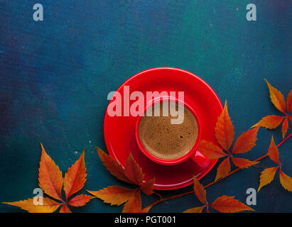 Tasse schwarzen Kaffee und Zweig der bunten Blätter im Herbst (Virginia Creeper) auf einem dunklen Blau-grün Holztisch. Flach Stockfoto