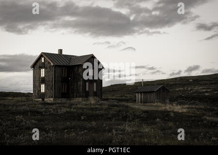 Ein altes Haus bei Sonnenuntergang, mit Sun Reflexionen in den Fenstern, in Storwartz, außerhalb von Røros, Norwegen. Stockfoto