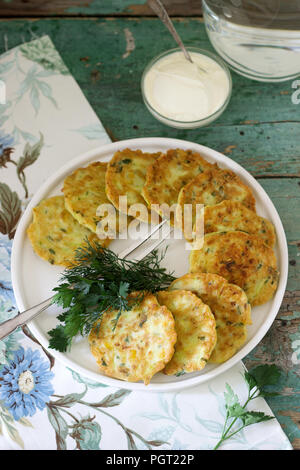 Pfannkuchen mit Zucchini und Mais, serviert mit saurer Sahne, Petersilie und Dill. Vegetarisches Essen, selektiven Fokus. Stockfoto