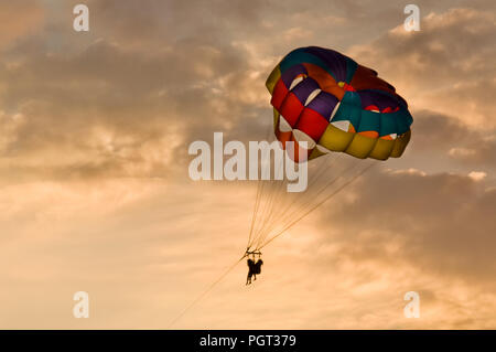 Menschen parasailing bei Sonnenuntergang in schönes Licht mit einem bunten Parasail. Stockfoto