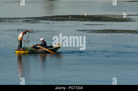 Ägyptische Männer im Boot mit Rudern fischen mit Netz im Morgenlicht mit Wasser Reflexionen, Nil, Ägypten, Afrika Stockfoto