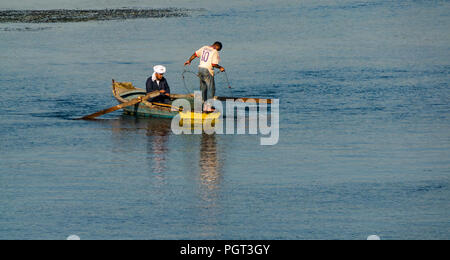Ägyptische Männer im Boot mit Rudern fischen mit Netz im Morgenlicht mit Wasser Reflexionen, Nil, Ägypten, Afrika Stockfoto