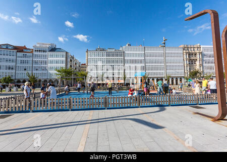 Kinder auf dem Spielplatz in der Avenida La Marina mit ihren typischen Glas Balkone und die La Marina Park, Parque La Marina, A Coruña, Galizien, Spanien Stockfoto