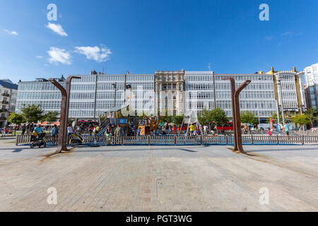 Kinder auf dem Spielplatz in der Avenida La Marina mit ihren typischen Glas Balkone und die La Marina Park, Parque La Marina, A Coruña, Galizien, Spanien Stockfoto