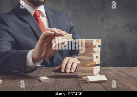 Unternehmer zieht Blocks von hölzernen Turm. Konzeption der Geschäftsstrategie. Stockfoto