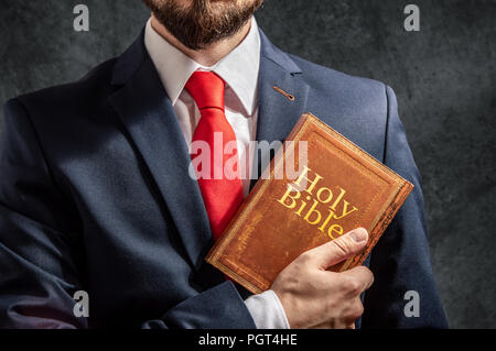 Mann sieht aus wie Politiker oder Unternehmer steht mit der heiligen Bibel Stockfoto