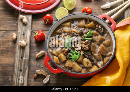 Massaman Curry mit Rindfleisch und Kartoffeln auf hölzernen Hintergrund Stockfoto