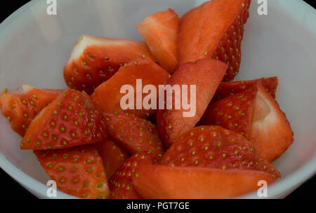 Stücke schneiden Erdbeeren in einem Glas in Schwarz Stockfoto