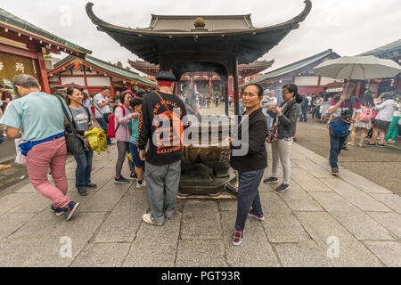 Asiatische Touristen während Räucherwerk Rauch reinigungsritual vor Jokoro auf Senso-ji Tempel in Asakusa. Tokio, Japan Stockfoto