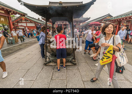 Asiatische Touristen während Räucherwerk Rauch reinigungsritual vor Jokoro auf Senso-ji Tempel in Asakusa. Tokio, Japan Stockfoto