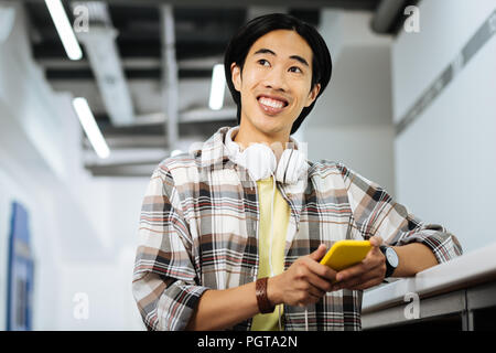 Asiatischer Mann glücklich und lächelnd seinen gelben Gadget Stockfoto