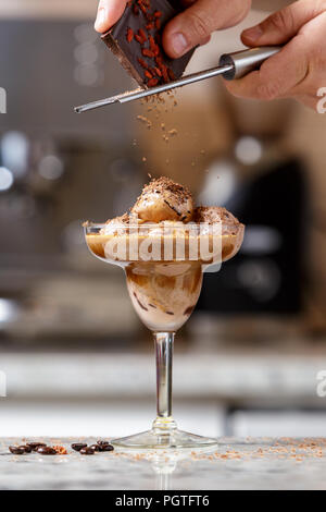 Die Hand des Mannes reiben Schokolade auf dem Affogato, espresso Eis Dessert im Glas Stockfoto