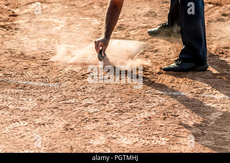 Schiedsrichter reinigt Home Plate in einem Baseball (Softball) staubigen Feld, mit Copyspace Stockfoto