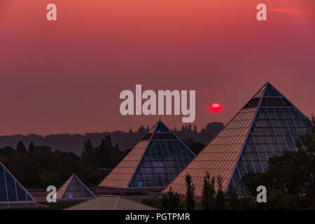 Sun steigt durch Rauch Himmel, Muttart Conservatory Pyramiden, Edmonton, Alberta, Kanada. Stockfoto