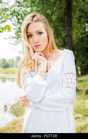 Junge hübsche Frau in weißem Kleid im Freien auf dem See in der Natur, meditieren Stockfoto