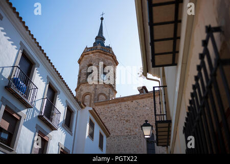 Tembleque, Spanien, ist ein kleines Dorf mit einer Kirche und einem Uhrenturm im Zentrum, das an einem Sommertag ohne Wolken am Himmel fotografiert wurde. Stockfoto