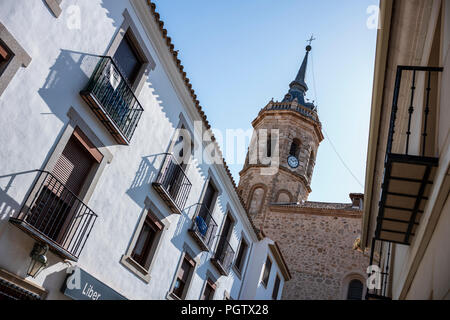 Tembleque, Spanien, ist ein kleines Dorf mit einer Kirche und einem Uhrenturm im Zentrum, das an einem Sommertag ohne Wolken am Himmel fotografiert wurde. Stockfoto