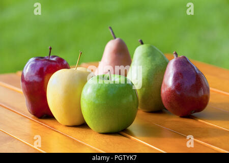Eine Vielzahl von Äpfeln und Birnen aufgereiht zusammen auf einem Tisch Stockfoto