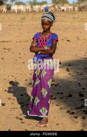 FERLO WÜSTE, SENEGAL - Apr 25, 2017: Unbekannter Fulbe Mädchen in heller Kleidung und Kopftuch Spaziergänge entlang der Straße. Fulanis (peul) sind die größten Stockfoto