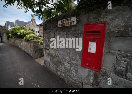 Red Post Box an einer Wand auf eine britische Straße Stockfoto