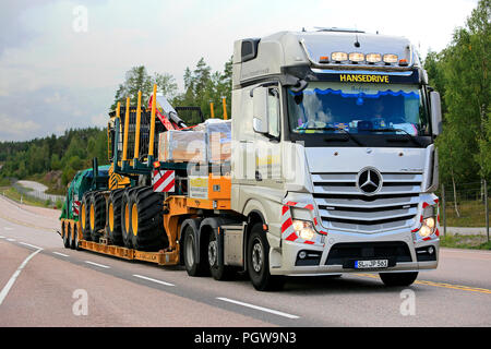 ORIVESI, Finnland - 27. AUGUST 2018: Mercedes-Benz Actros Sattelschlepper von Hansedrive Transporte Forstmaschinen auf der Autobahn in Finnland an bewölkten Tag. Stockfoto