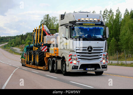 ORIVESI, Finnland - 27. AUGUST 2018: Mercedes-Benz Actros Sattelschlepper von Hansedrive Transporte Forstmaschinen auf der Autobahn in Finnland an bewölkten Tag. Stockfoto