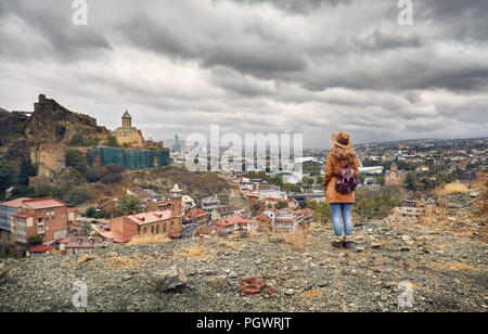 Frau in braunen Hut und Rucksack suchen an der alten mittelalterlichen Burg Narikala mit bedeckt bewölkten Himmel in Tiflis, Georgien Stockfoto