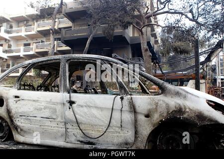 Menschen stehen unter den Verkohlten von ausgebrannten Autos in Mati östlich von Athen, zwei Waldbrände durch den beliebten Badeort Bereiche in der Nähe des griechischen Raging ca Stockfoto