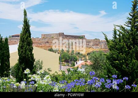 Blick auf das Schloss und die Stadt Gebäude aus der San Antonio Kapelle Gärten mit hübschen Allium Blumen im Vordergrund gesehen, Castro Marim, Algarve, Po Stockfoto