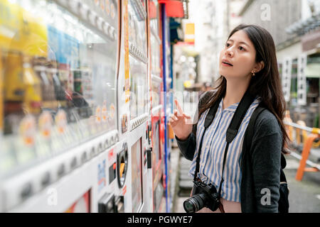 Asiatische Frau Wahl, was zu trinken. Stehen und Denken vor der Automaten CNC. Stockfoto