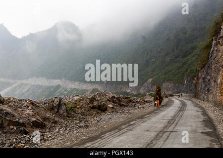 Ha Giang, Vietnam - 17. März 2018: weibliche Arbeitnehmer in der Landwirtschaft den Transport von großen Lasten von Pflanzen auf einer Straße in den Bergen im Norden von Vietnam Stockfoto