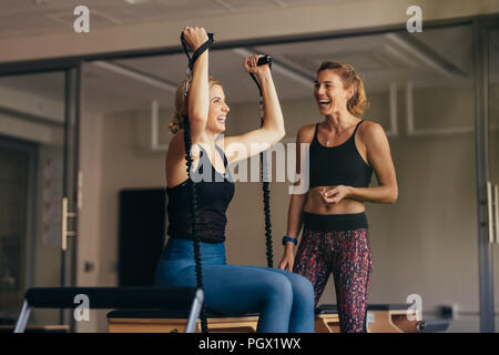 Lächelnde Frau ziehen stretch Bands während ihrer Pilates Training. Frauen an einem Pilates Training Turnhalle lachen, während Sie trainieren. Stockfoto