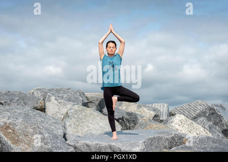 Frau, Yoga, Baum darstellen, trägt ein T-Shirt mit "Balance"-Slogan. Stockfoto