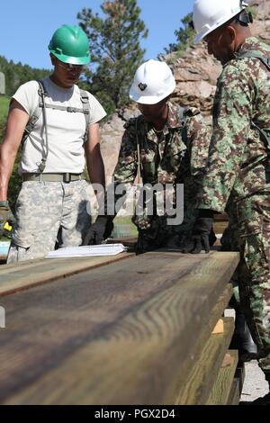 Us-Armee SPC. Fred Grinnell mit den 155 Ingenieur Firma, South Dakota Nationalgarde und Soldaten aus der Firma Maitenance von Suriname Suriname Defence Force, gehen über Pläne während einer Brücke reparieren Projekt zur Unterstützung von Golden Coyote, Totholz, S.D., 15. Juni 2018. Die goldenen Coyote Übung ist eine dreiphasige, Szenario-driven Übung in den Black Hills von South Dakota und Wyoming, mit dem Kommandanten auf der Mission wesentliche Anforderungen der Aufgabe, Krieger Aufgaben und Übungen zu konzentrieren. Stockfoto