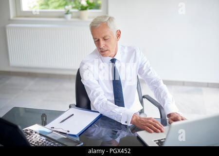 High Angle Shot eines Senior Financial Advisor Geschäftsmanns, der auf seinem Laptop im Büro. Stockfoto