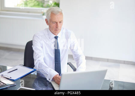 High Angle Shot der Geschäftsmann mit seinem Laptop und Eingabe über Tastatur, während der Arbeit im Büro. Stockfoto