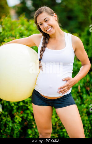 Gerne schwangere Frau berühren Bauch Halten Fitness Ball Stockfoto