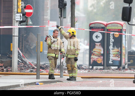 Feuerwehrmänner weiter die Szene am Primark store in der historischen 5-stöckigen Bank Gebäude im Stadtzentrum von Belfast, wo ein großbrand am Dienstag brachen zu besuchen. Stockfoto