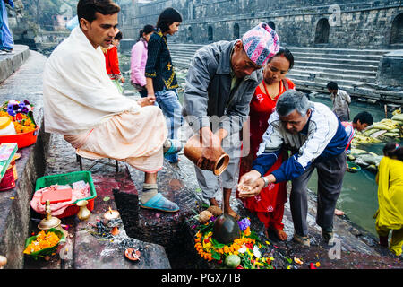 Pashupatinath Tempel, Kathmandu Tal, Bagmati, Nepal, Südafrika Asien: ein Priester den Gläubigen die religiöse Angebote im Shiva Lingam auf t teilnehmen Stockfoto