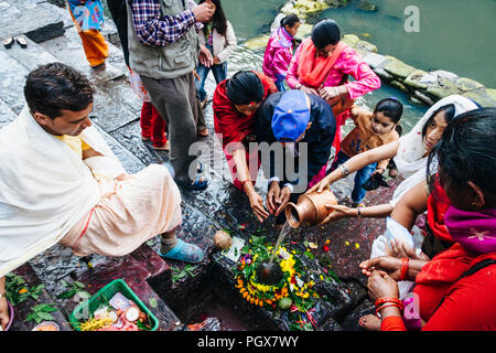 Pashupatinath Tempel, Kathmandu Tal, Bagmati, Nepal, Südafrika Asien: ein Priester den Gläubigen die religiöse Angebote im Shiva Lingam auf t teilnehmen Stockfoto