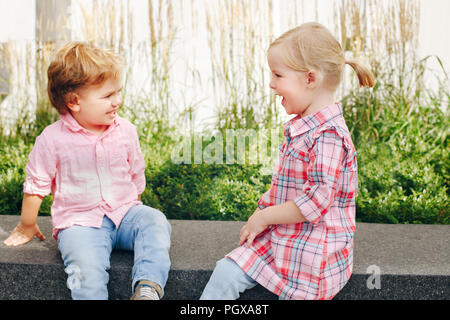 Group Portrait von zwei weissen Kaukasischen cute adorable lustig Kinder Kleinkinder sitzen zusammen reden lächelnd. Liebe Freundschaft fun Konzept. Bester Freund Stockfoto