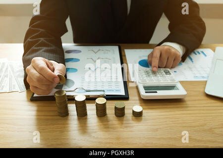 Geschäftsmann nimmt Münzen auf den Tisch und zählt Geld. Geschäftskonzept. Stockfoto