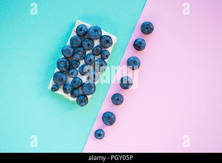 Köstliche frisch gepflückte bluberry und gesunde Sandwich auf blau und rosa Hintergrund mit Copyspace. Gesunde Ernährung Konzept. Stockfoto
