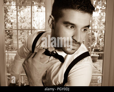 Business, Mann im Smoking sitzt neben Fenster mit Blick auf Garten Stockfoto