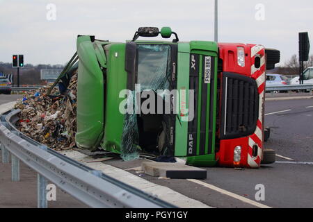 Ein Lkw umkippt und Leckagen ist es Laden der Verwertung von Abfällen über die neue Fahrbahn der Großen Yorkshire in Doncaster, South Yorkshire Stockfoto