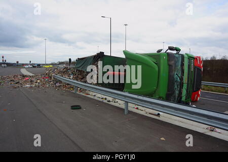 Ein Lkw umkippt und Leckagen ist es Laden der Verwertung von Abfällen über die neue Fahrbahn der Großen Yorkshire in Doncaster, South Yorkshire Stockfoto