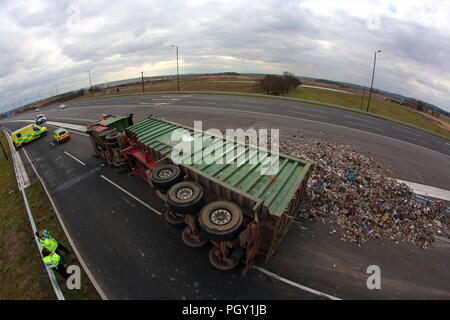 Ein Lkw umkippt und Leckagen ist es Laden der Verwertung von Abfällen über die neue Fahrbahn der Großen Yorkshire in Doncaster, South Yorkshire Stockfoto