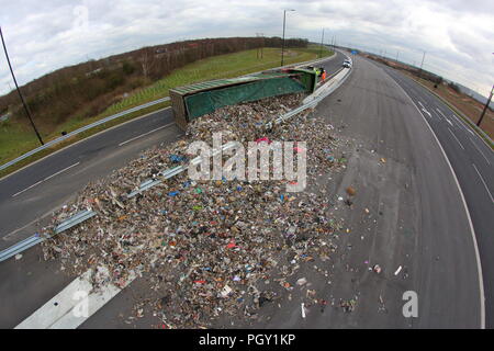 Ein Lkw umkippt und Leckagen ist es Laden der Verwertung von Abfällen über die neue Fahrbahn der Großen Yorkshire in Doncaster, South Yorkshire Stockfoto