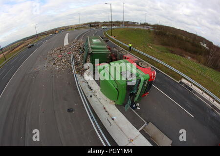 Ein Lkw umkippt und Leckagen ist es Laden der Verwertung von Abfällen über die neue Fahrbahn der Großen Yorkshire in Doncaster, South Yorkshire Stockfoto